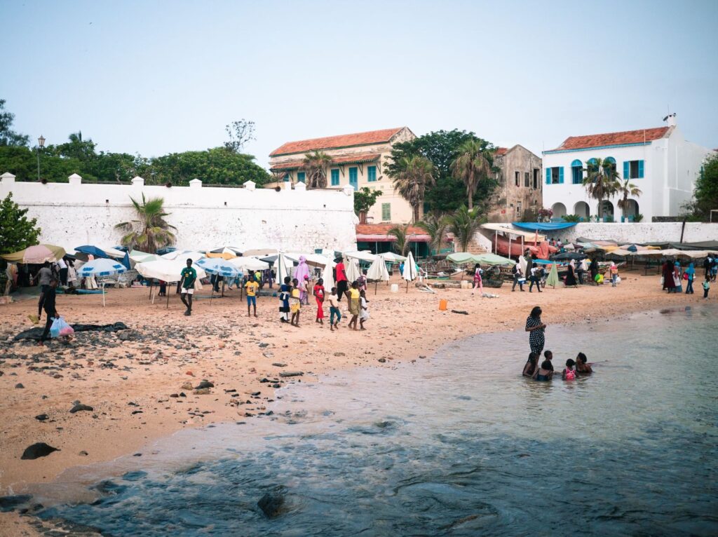 Lively beach scene with people enjoying the coastline near historic buildings.